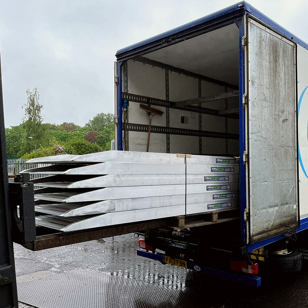 Picture of truck loading ramps. Truck loading ramps stacked on top of each other. Truck loading ramp being loaded into a truck..