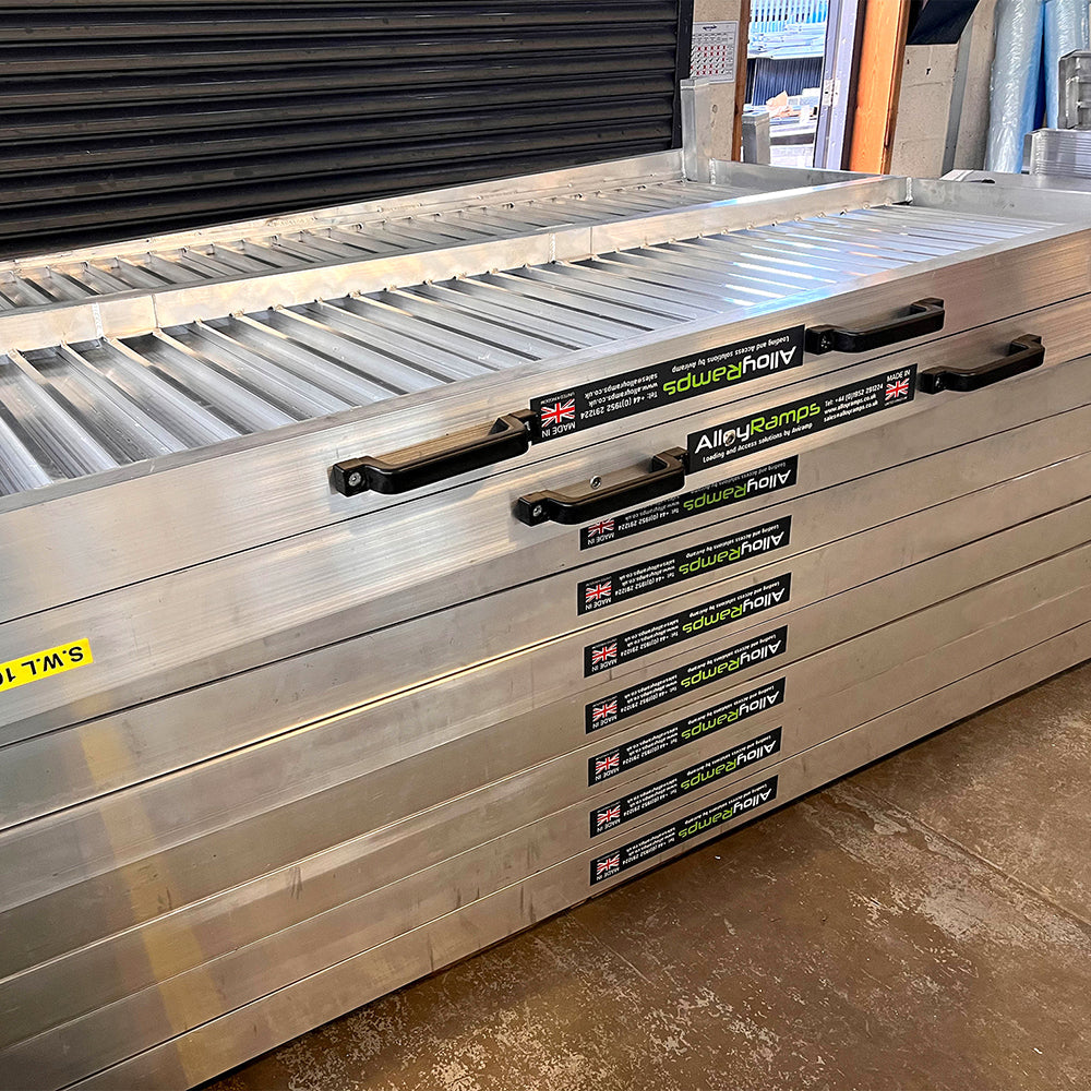 Picture of truck loading ramps. Truck loading ramps stacked on top of each other. Truck loading ramp being loaded into a truck..